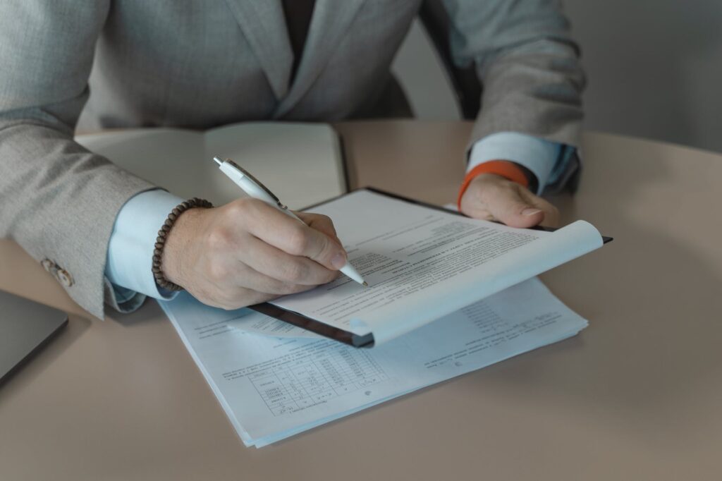 person in white long sleeve shirt holding pen and white paper